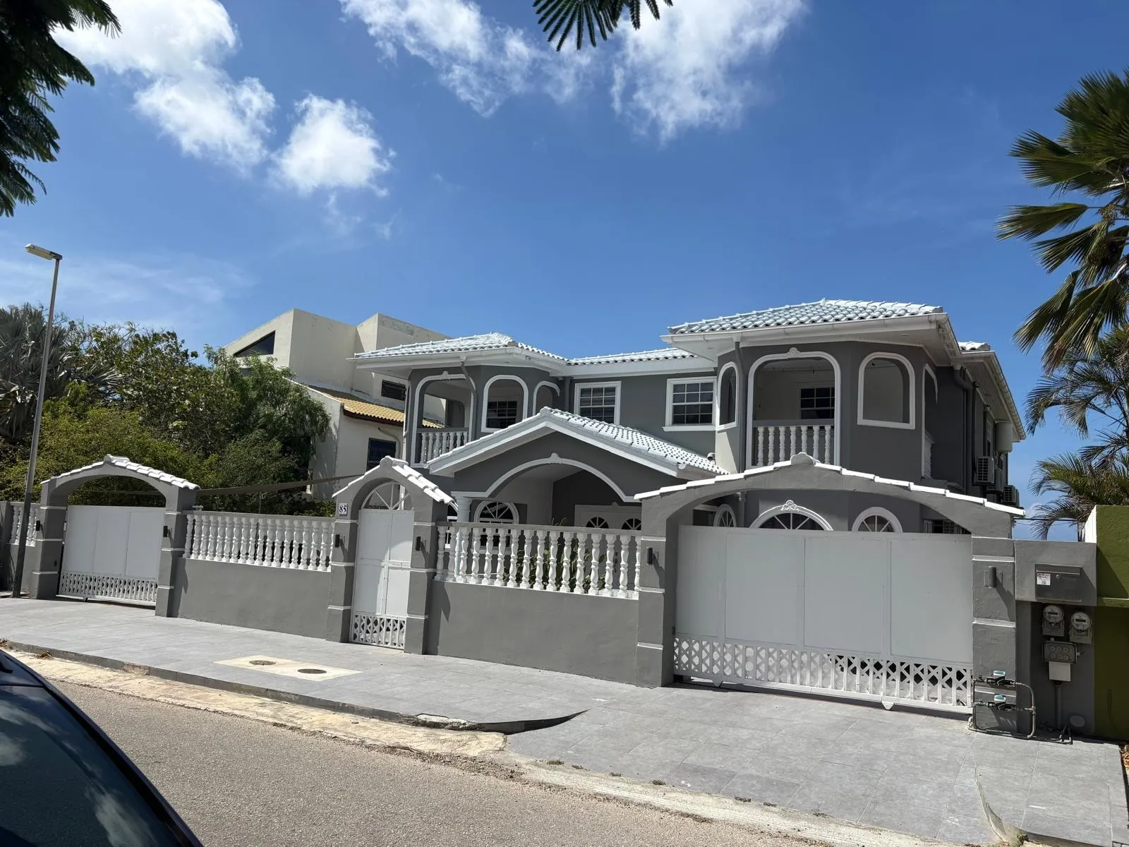 Vrijstaande woning op Curaçao, buitenmuren in grijs met wit lijstwerk, balustrades en poorten
