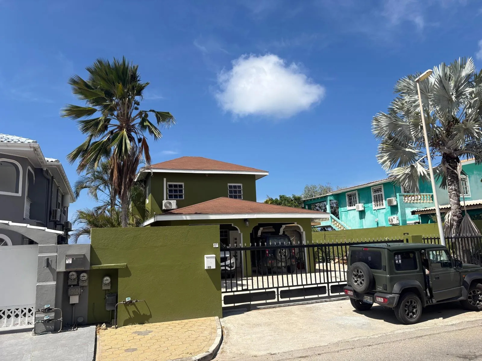 Woning op Curaçao met olijfgroen geschilderde gevel en erfmuur